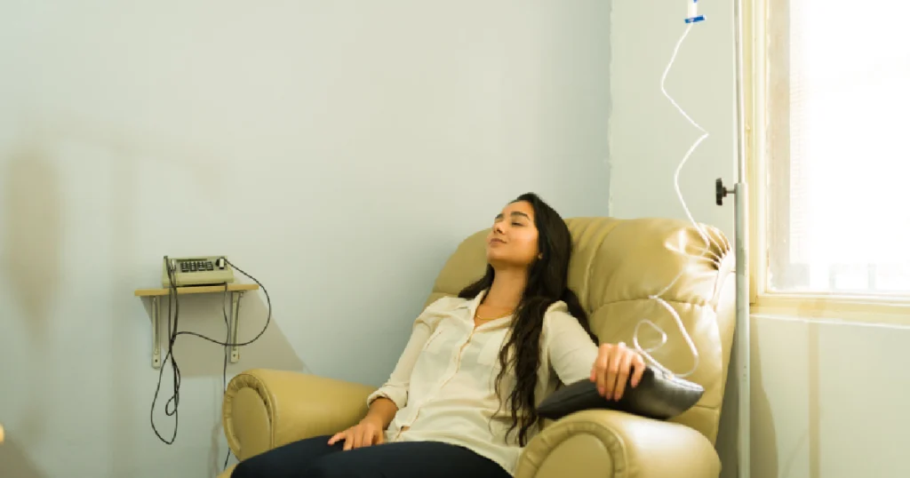 Woman relaxing in a recliner chair while receiving IV therapy through a drip, near a window in a wellness or medical clinic setting in Yuma, AZ
